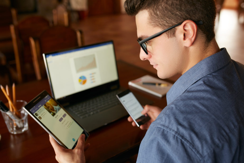 man in glasses holding multiple devices